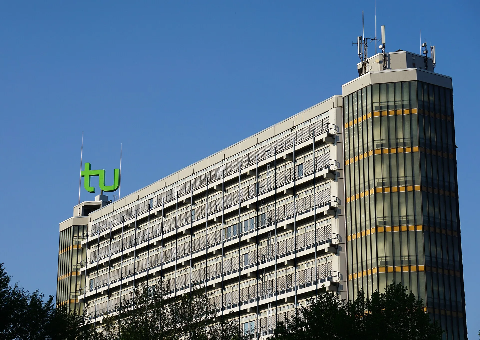 The TU Dortmund Mathetower against a clear blue sky, the green tu logo on its roof